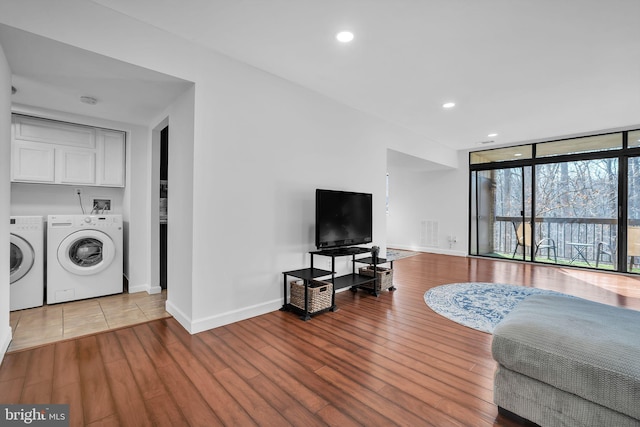 living room featuring a wall of windows, wood finished floors, visible vents, and separate washer and dryer