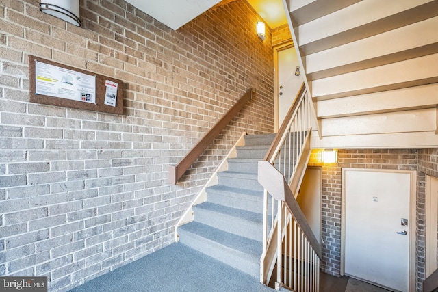 stairs with carpet and brick wall