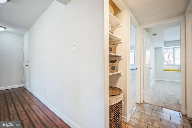 hall with baseboards and tile patterned floors