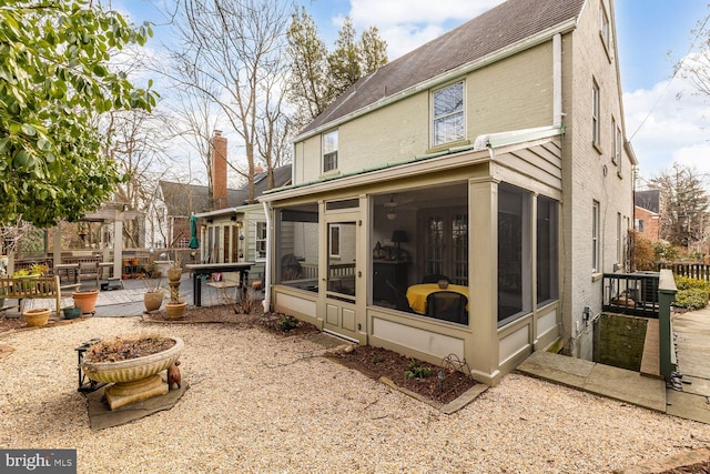 back of property featuring a sunroom, fence, and brick siding