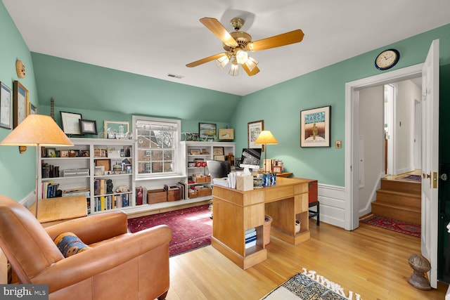 office featuring light wood-style floors, visible vents, vaulted ceiling, and a ceiling fan