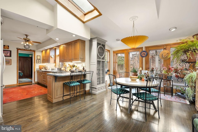 dining space featuring ceiling fan, vaulted ceiling with skylight, dark wood finished floors, and recessed lighting