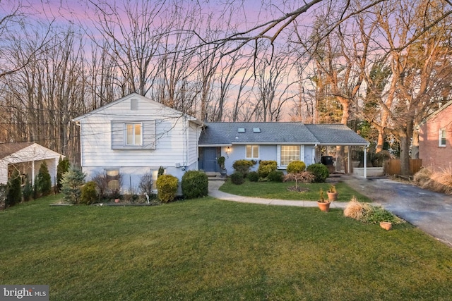 tri-level home featuring an attached carport, driveway, and a lawn