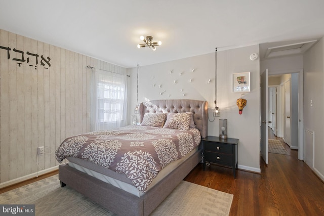 bedroom featuring attic access, wood finished floors, baseboards, and wood walls