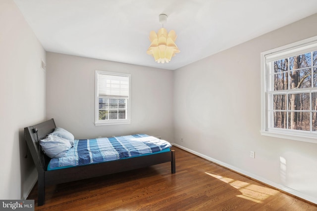 bedroom featuring wood finished floors, baseboards, and a chandelier