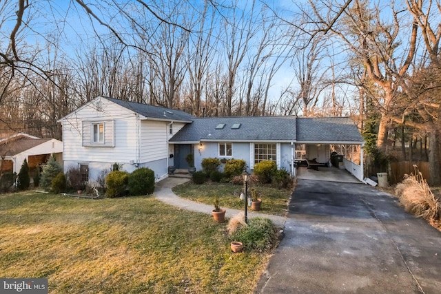 tri-level home featuring an attached carport, driveway, a shingled roof, and a front lawn