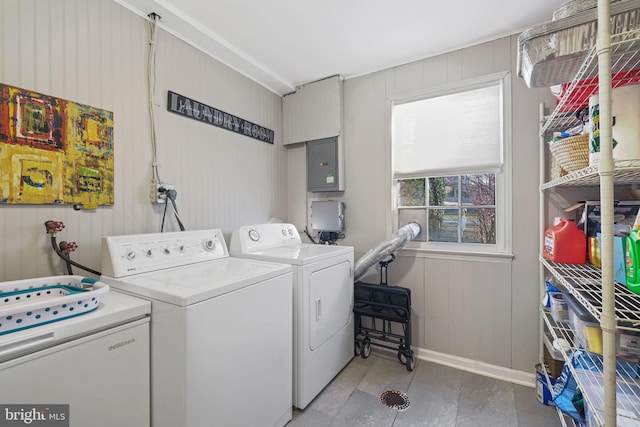 laundry room featuring laundry area, electric panel, baseboards, and washer and clothes dryer