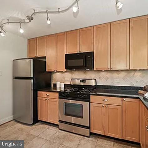 kitchen featuring dark countertops, baseboards, appliances with stainless steel finishes, and backsplash