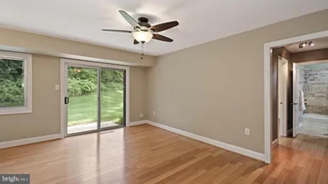 empty room featuring light wood finished floors, ceiling fan, and baseboards