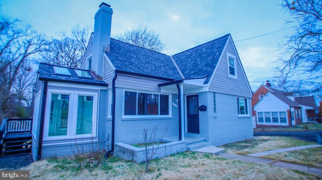 view of front of home featuring a front yard, brick siding, and a chimney