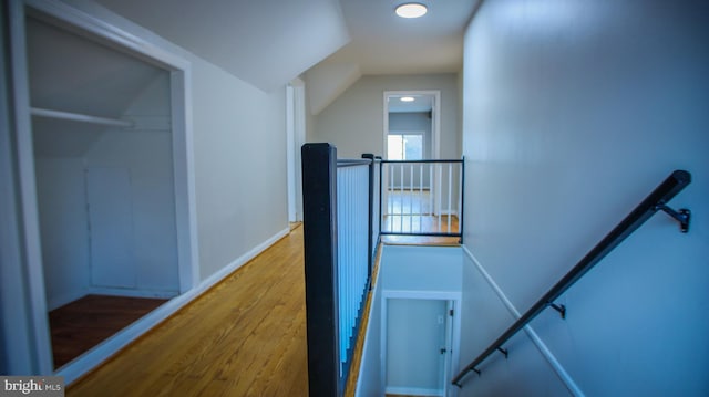 stairs with baseboards, wood finished floors, and vaulted ceiling