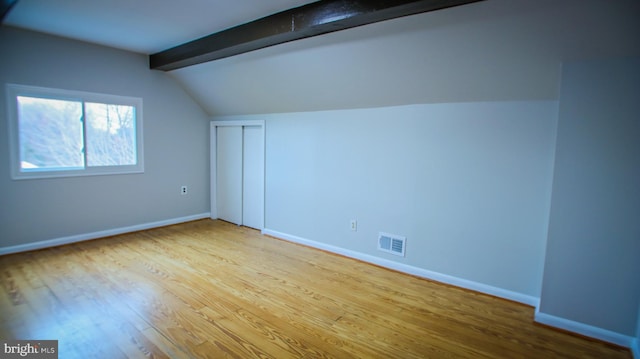 additional living space with visible vents, baseboards, wood finished floors, and vaulted ceiling with beams