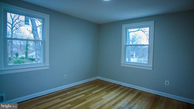 spare room featuring visible vents, baseboards, and wood finished floors