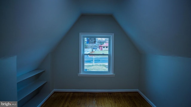 bonus room with dark wood-style floors, baseboards, and vaulted ceiling