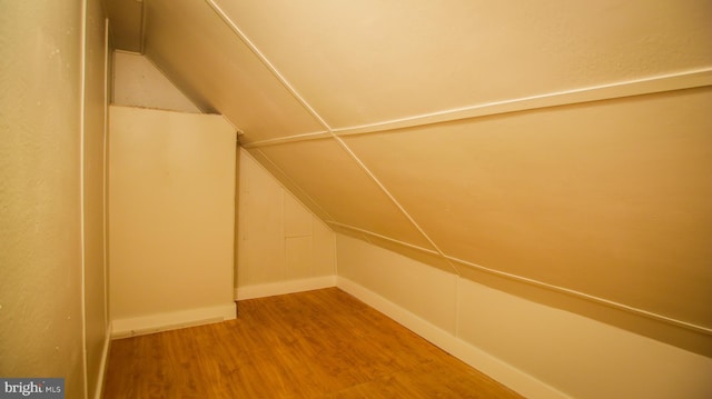 additional living space with baseboards, lofted ceiling, and wood finished floors