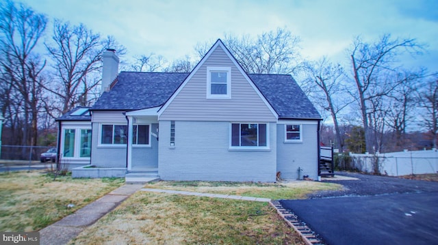 view of front of property with a front lawn, fence, brick siding, and a chimney