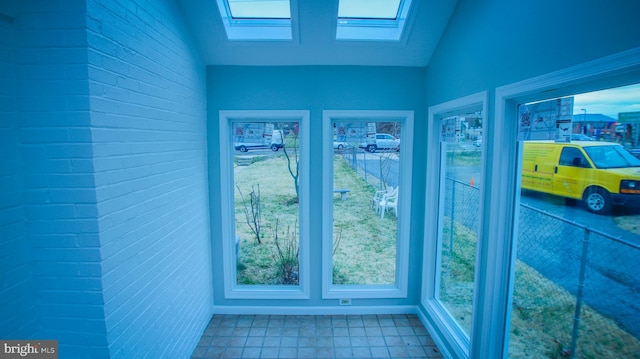 unfurnished sunroom featuring vaulted ceiling with skylight