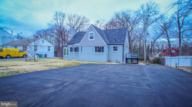 view of front of home featuring a front lawn, fence, brick siding, and a chimney