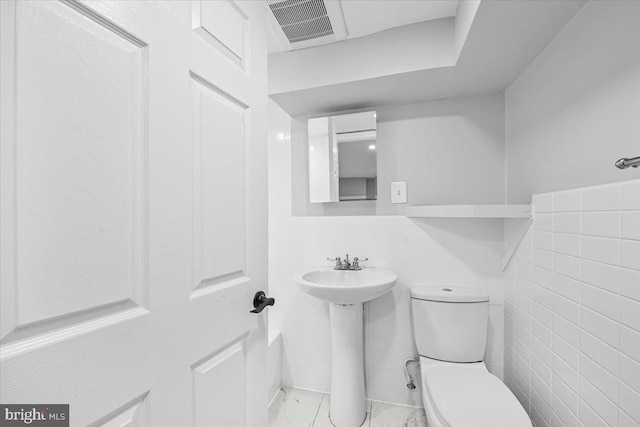 bathroom with visible vents, toilet, and tile walls