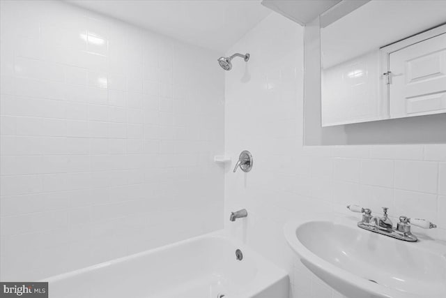 bathroom featuring decorative backsplash, shower / bathing tub combination, tile walls, and a sink