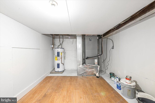 utility room featuring heating unit and electric water heater