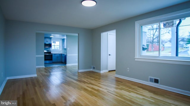 spare room featuring visible vents, baseboards, and wood finished floors