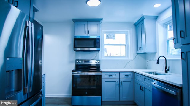 kitchen with baseboards, appliances with stainless steel finishes, and a sink