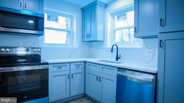 kitchen with appliances with stainless steel finishes, light countertops, and a sink