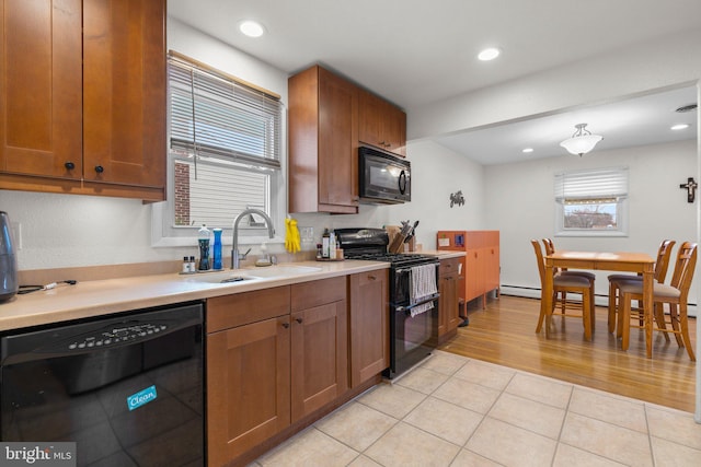 kitchen featuring brown cabinets, black appliances, light countertops, and a sink