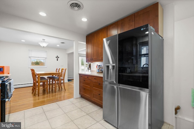 kitchen with light tile patterned floors, brown cabinetry, visible vents, stainless steel fridge with ice dispenser, and range with electric cooktop