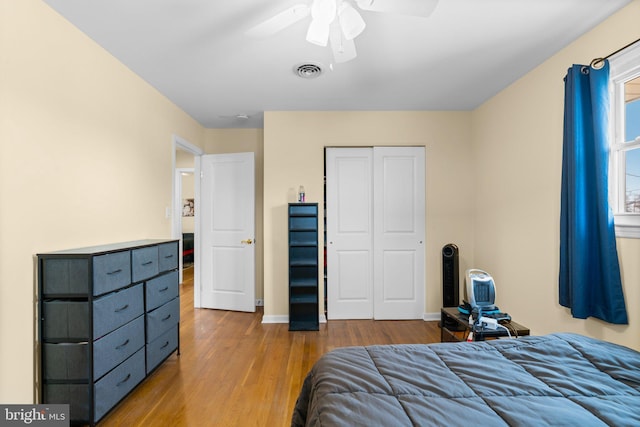 bedroom with visible vents, wood finished floors, a closet, baseboards, and ceiling fan