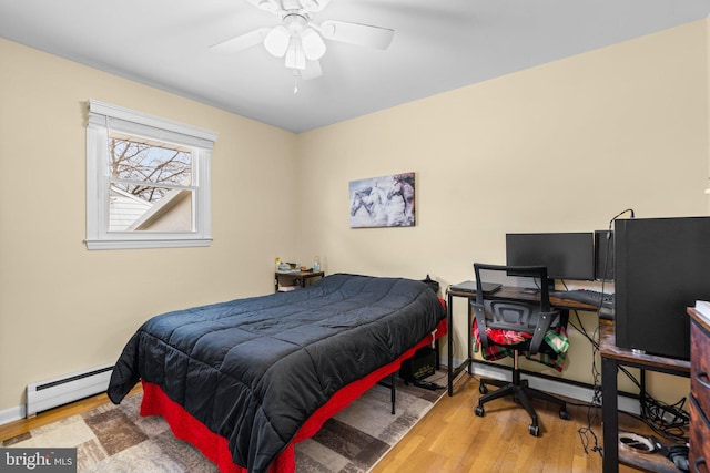 bedroom with baseboard heating, a ceiling fan, baseboards, and wood finished floors