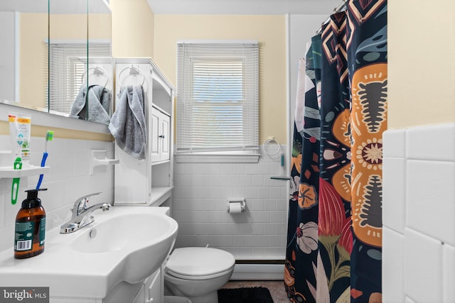 full bath featuring toilet, a shower with shower curtain, baseboard heating, tile walls, and a sink