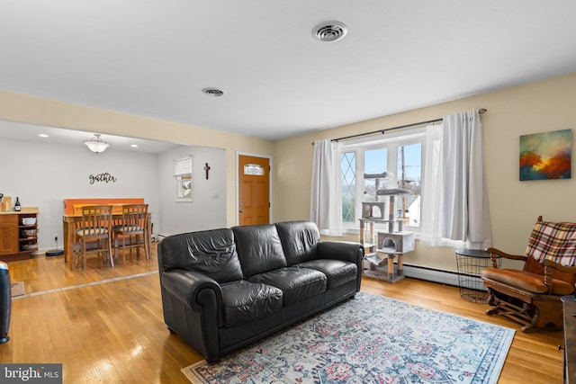 living room featuring visible vents, light wood-style floors, and a baseboard radiator