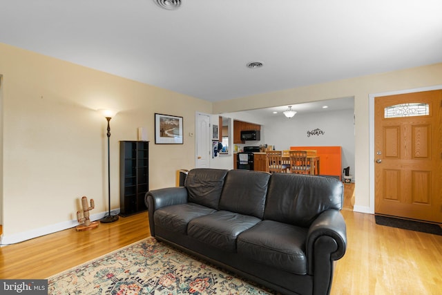 living room with visible vents, baseboards, and light wood-style floors