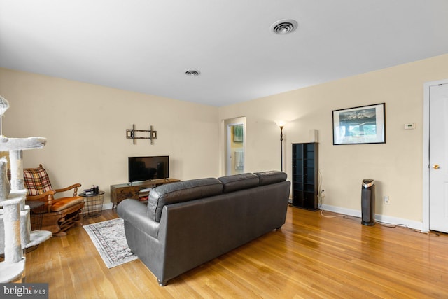 living room featuring visible vents, baseboards, and light wood finished floors