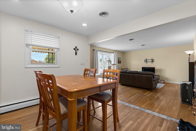 dining area featuring wood finished floors, a baseboard radiator, and a healthy amount of sunlight