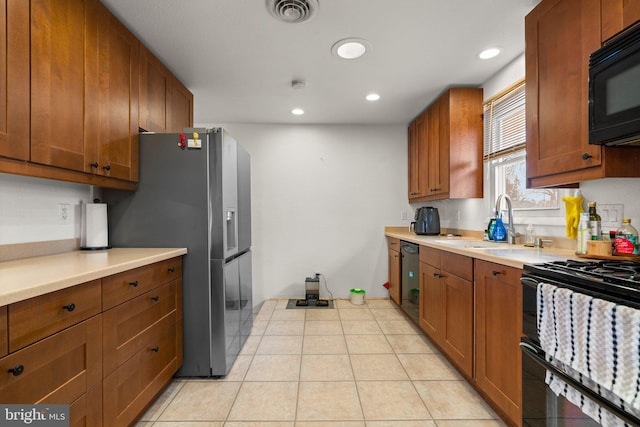 kitchen with visible vents, light tile patterned flooring, a sink, black appliances, and brown cabinets