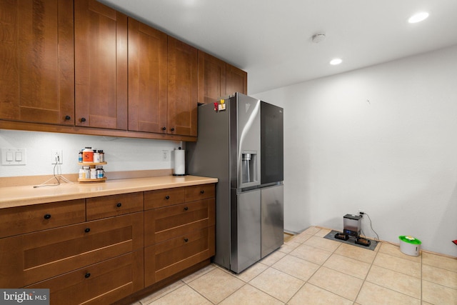 kitchen featuring light tile patterned floors, brown cabinetry, stainless steel fridge, and light countertops