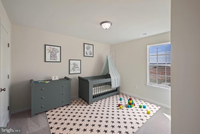 carpeted bedroom featuring a crib and baseboards