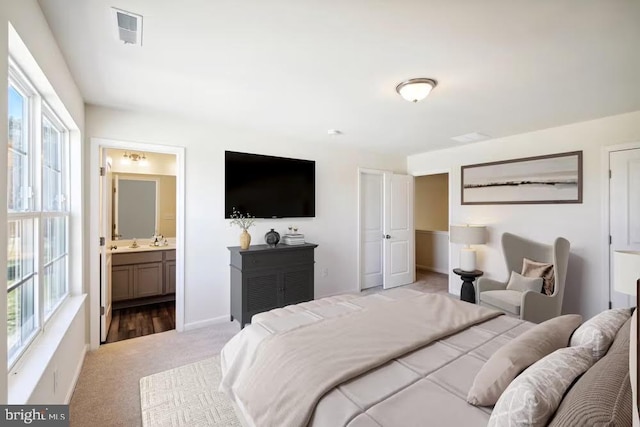 bedroom featuring visible vents, connected bathroom, light carpet, and multiple windows