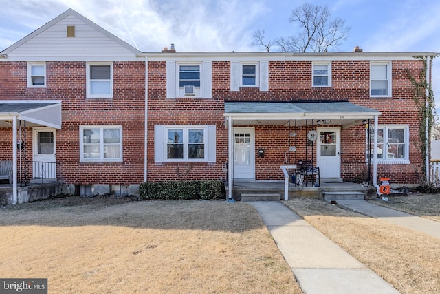 multi unit property featuring a front yard, a porch, and brick siding