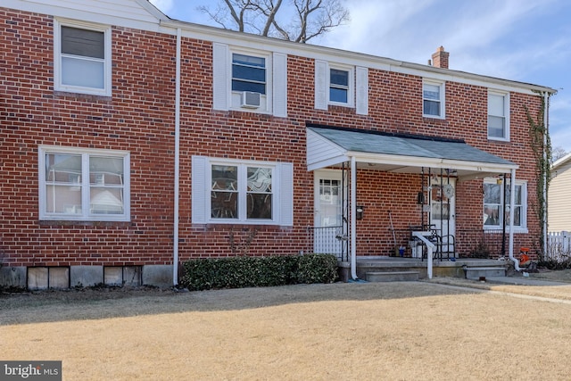 townhome / multi-family property featuring a chimney, a porch, cooling unit, and brick siding