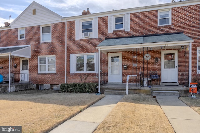 townhome / multi-family property with brick siding, a chimney, a porch, and cooling unit