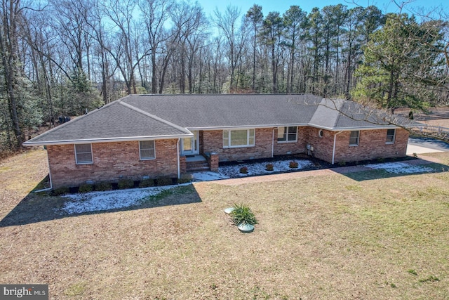 ranch-style house with a front lawn, roof with shingles, and brick siding