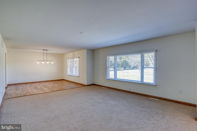 empty room featuring carpet flooring, visible vents, and baseboards