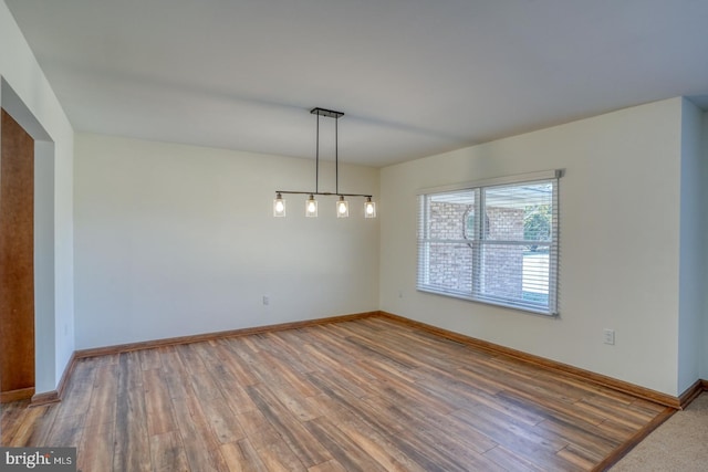 unfurnished room with baseboards and wood finished floors