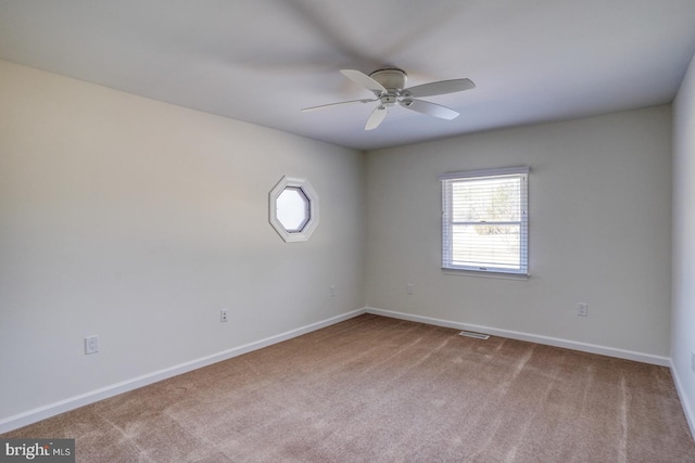 spare room with carpet floors, visible vents, ceiling fan, and baseboards