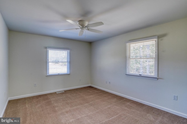 unfurnished room with carpet flooring, visible vents, and baseboards