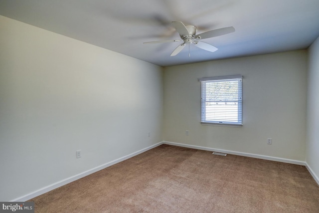 carpeted spare room with ceiling fan, visible vents, and baseboards